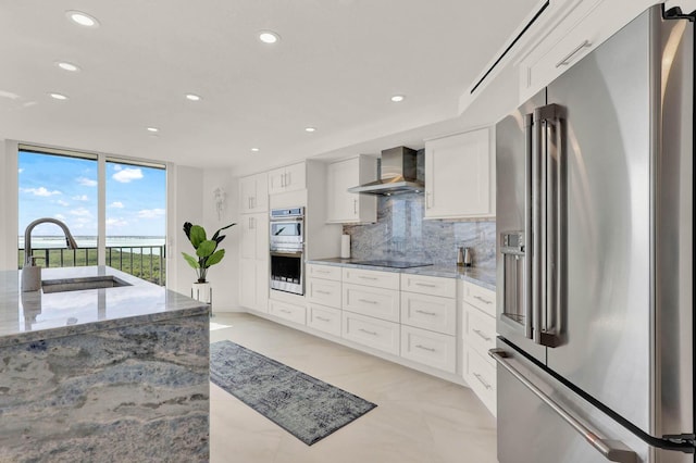 kitchen featuring appliances with stainless steel finishes, sink, white cabinets, and wall chimney exhaust hood