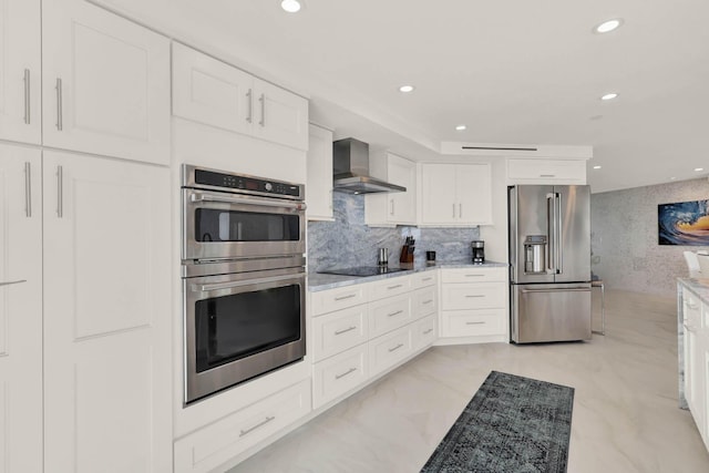 kitchen featuring wall chimney range hood, appliances with stainless steel finishes, light stone counters, white cabinets, and decorative backsplash