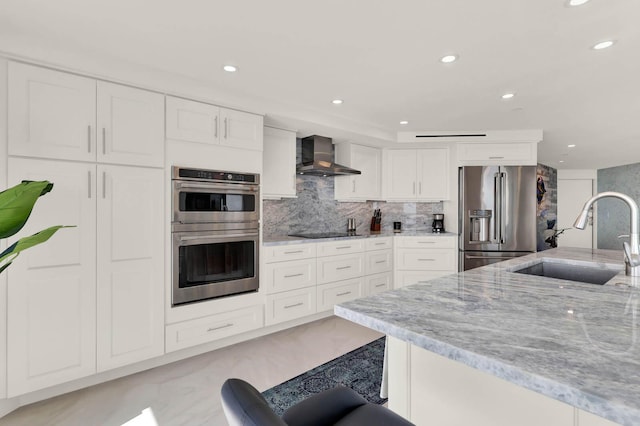 kitchen featuring appliances with stainless steel finishes, sink, a breakfast bar area, white cabinets, and wall chimney range hood