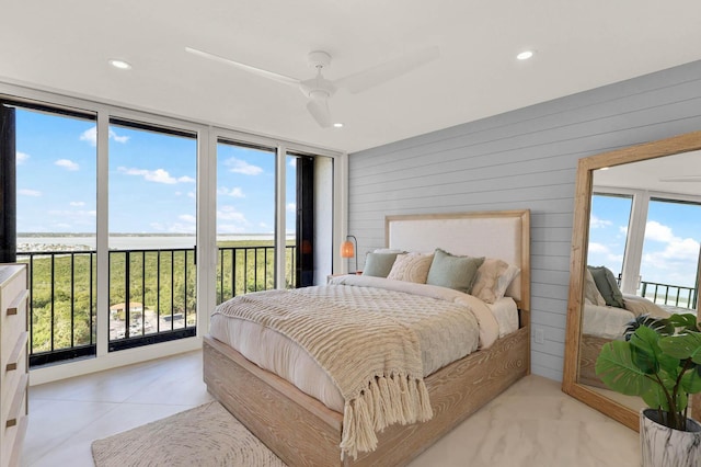 bedroom featuring a water view, access to exterior, ceiling fan, and wood walls