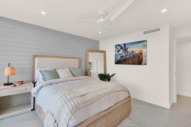 bedroom featuring ceiling fan and wooden walls