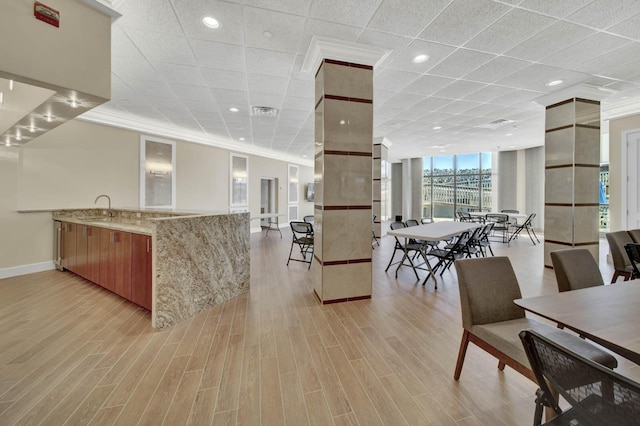 kitchen featuring sink, crown molding, light hardwood / wood-style floors, light stone countertops, and expansive windows