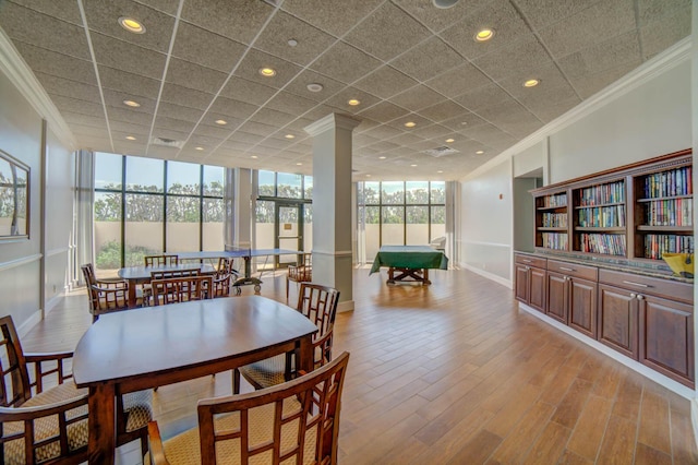 dining area with a paneled ceiling, ornamental molding, floor to ceiling windows, and light wood-type flooring