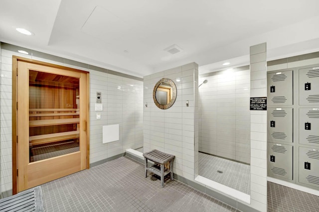 bathroom with tile patterned flooring, tiled shower, and tile walls