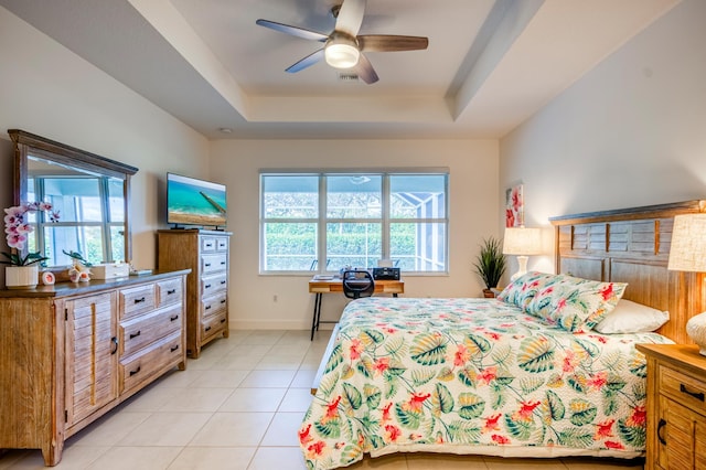 tiled bedroom featuring ceiling fan, a raised ceiling, and multiple windows