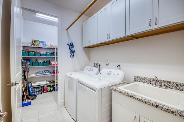 laundry area featuring separate washer and dryer, sink, light tile patterned floors, and cabinets