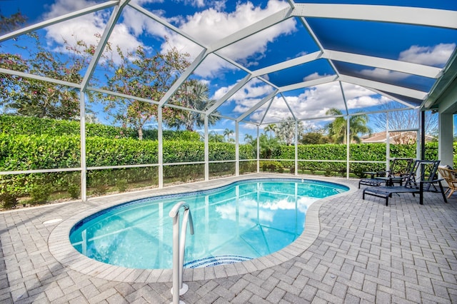 view of pool with glass enclosure and a patio area