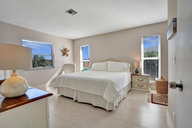 bedroom with multiple windows, light tile patterned floors, and a textured ceiling