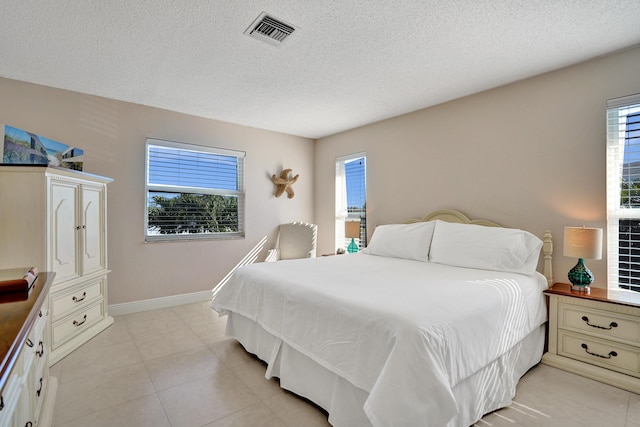 bedroom with multiple windows, light tile patterned floors, and a textured ceiling