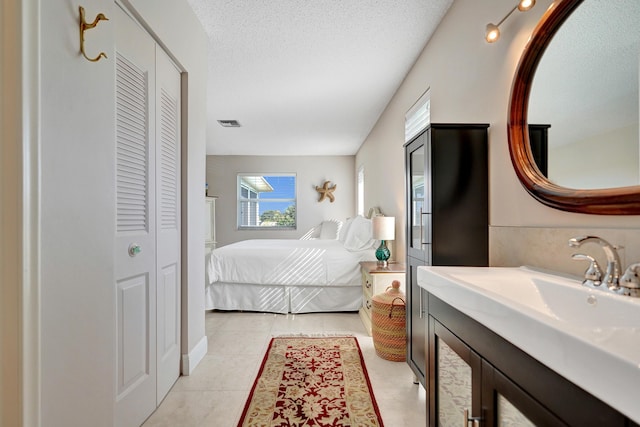 tiled bedroom with sink and a textured ceiling