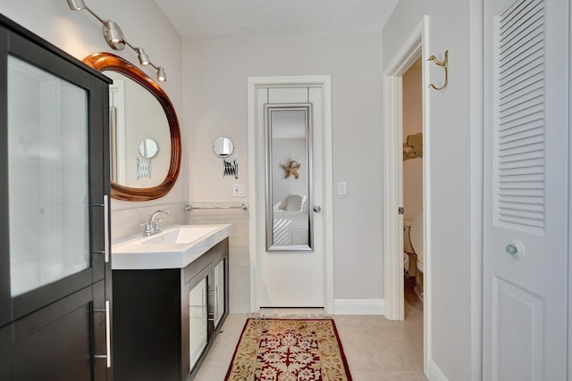 bathroom with vanity, toilet, tile patterned flooring, and a textured ceiling