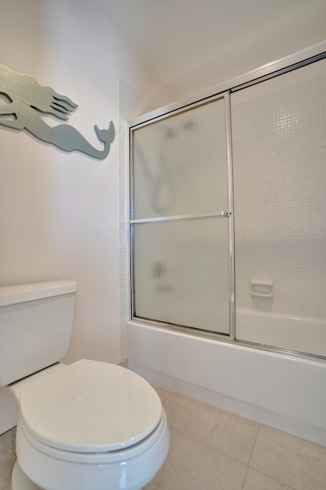 bathroom with tile patterned flooring, bath / shower combo with glass door, and toilet