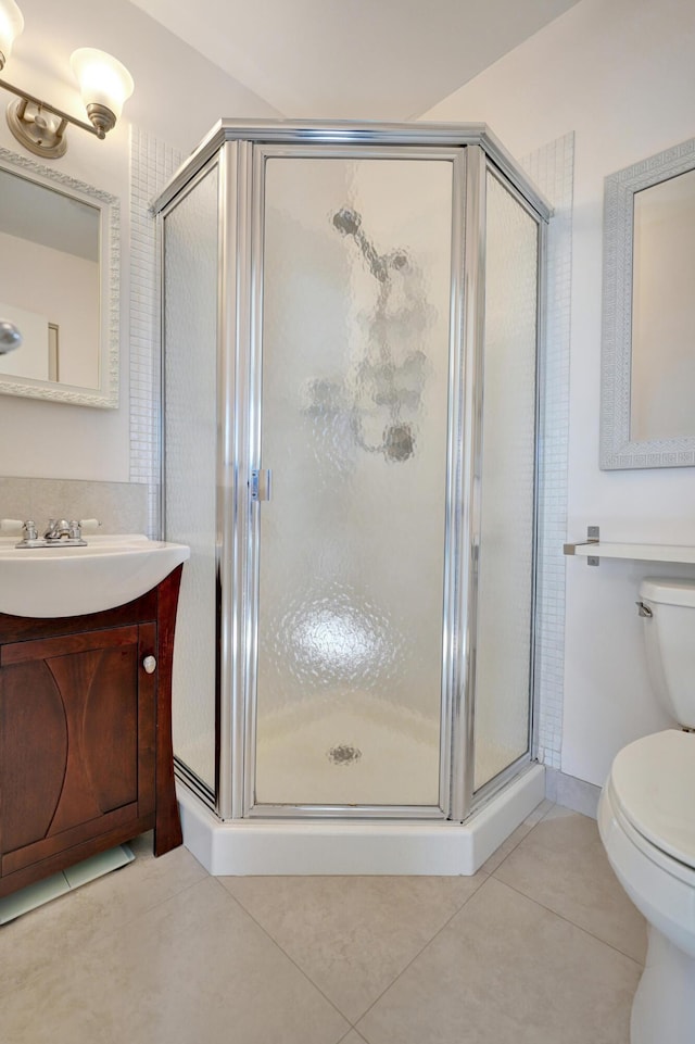 bathroom with toilet, vanity, a shower with door, and tile patterned flooring