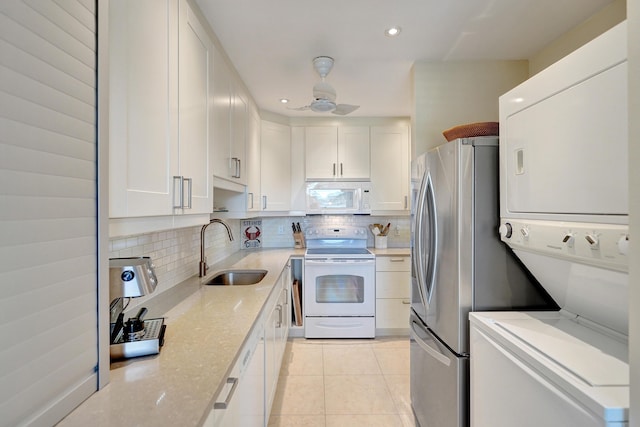 kitchen featuring sink, white appliances, backsplash, light stone countertops, and white cabinets