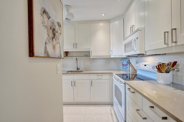 kitchen with sink, white appliances, white cabinetry, tasteful backsplash, and light stone counters