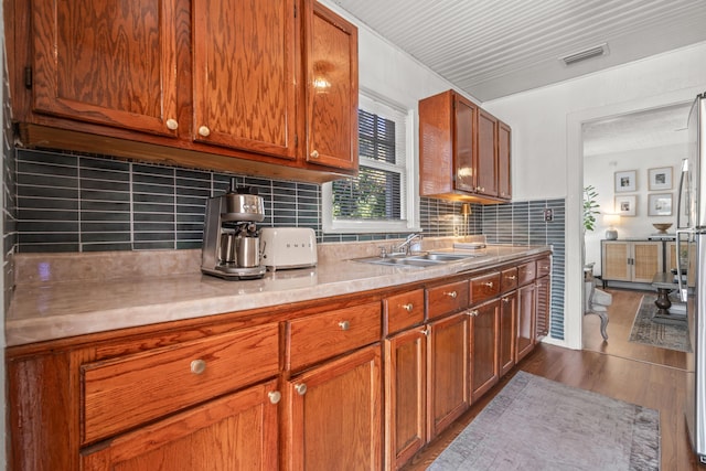 kitchen featuring sink, backsplash, and wood-type flooring