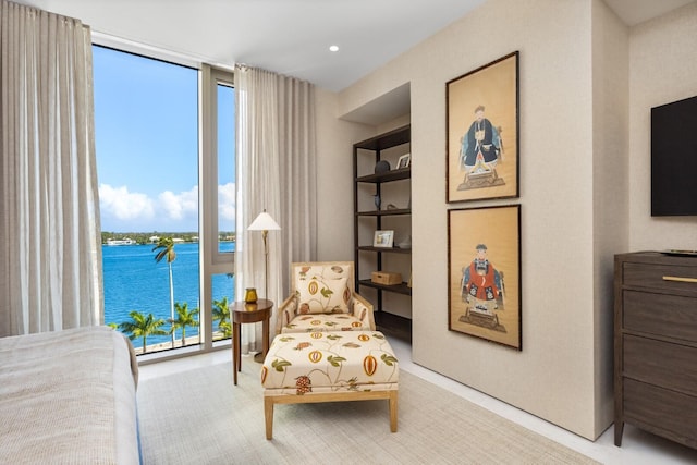 sitting room featuring built in shelves, a wall of windows, and a water view