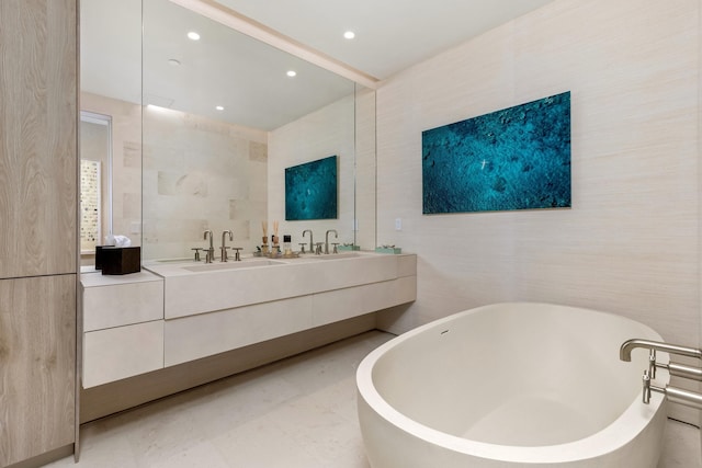 full bathroom with double vanity, recessed lighting, a freestanding bath, and a sink