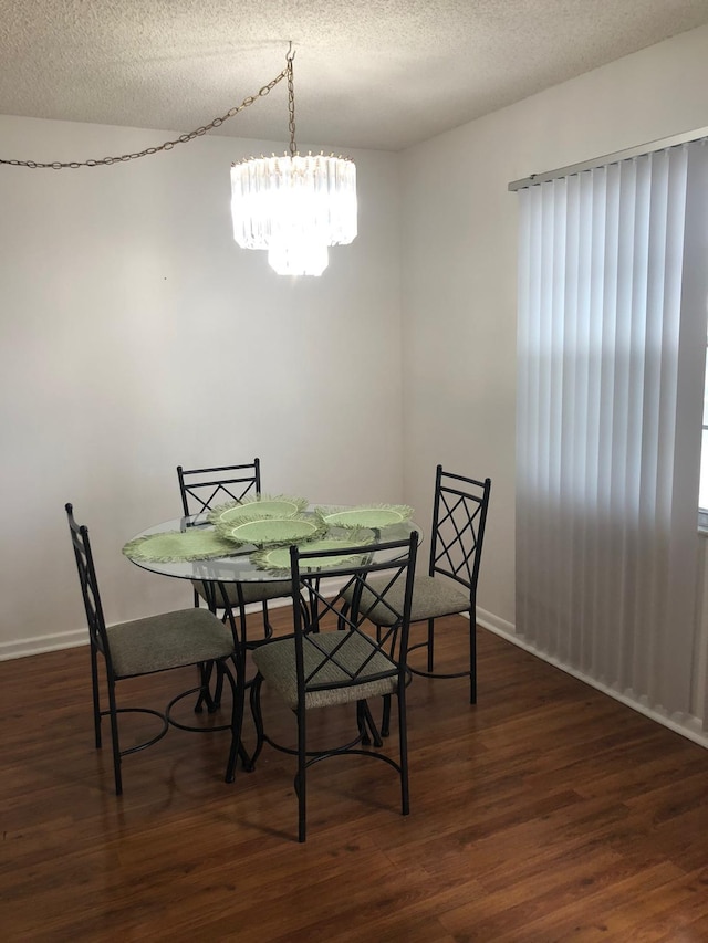 dining area featuring dark hardwood / wood-style flooring, a notable chandelier, and a textured ceiling