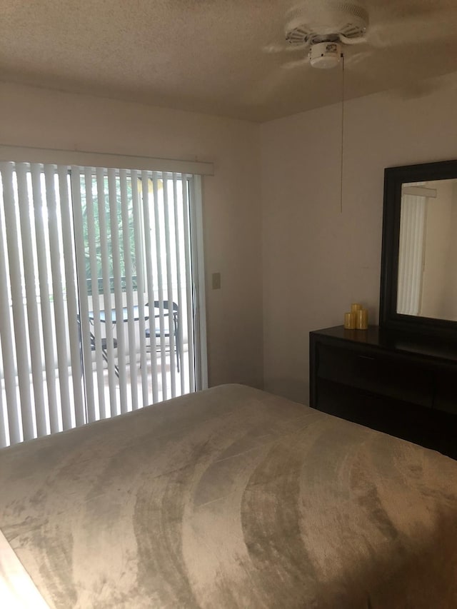 bedroom featuring access to exterior, a textured ceiling, and ceiling fan