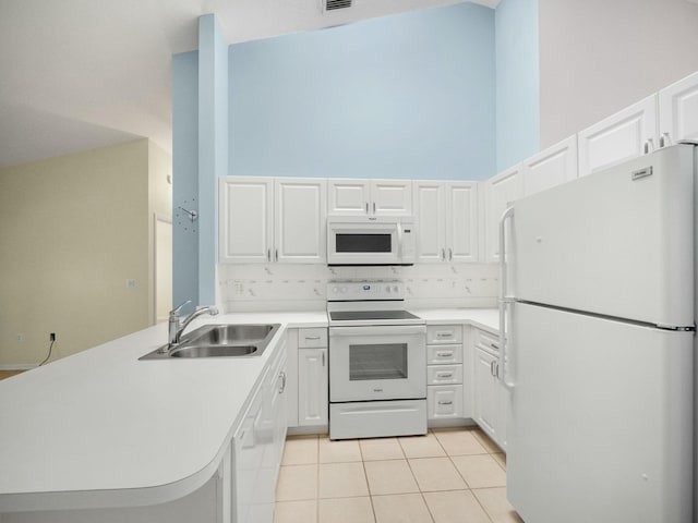 kitchen featuring white appliances, a towering ceiling, tasteful backsplash, white cabinets, and kitchen peninsula