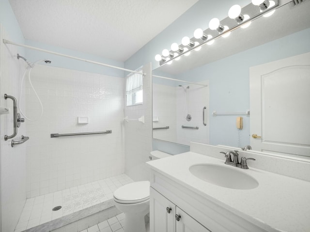 bathroom featuring toilet, a textured ceiling, a tile shower, vanity, and tile patterned flooring