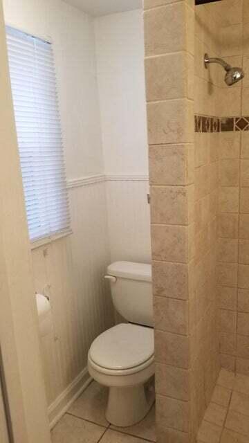 bathroom featuring tile patterned floors, toilet, and tiled shower