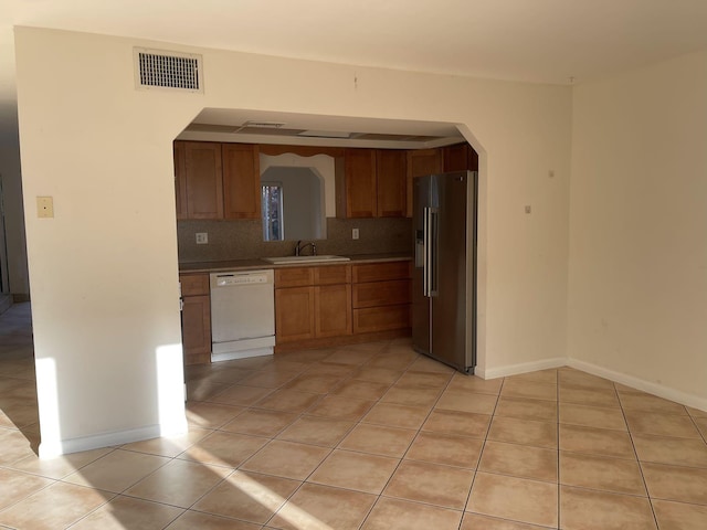 kitchen featuring tasteful backsplash, dishwasher, sink, high end refrigerator, and light tile patterned floors