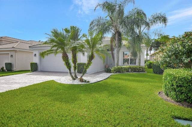 view of front of house featuring a front lawn, a tile roof, stucco siding, decorative driveway, and a garage