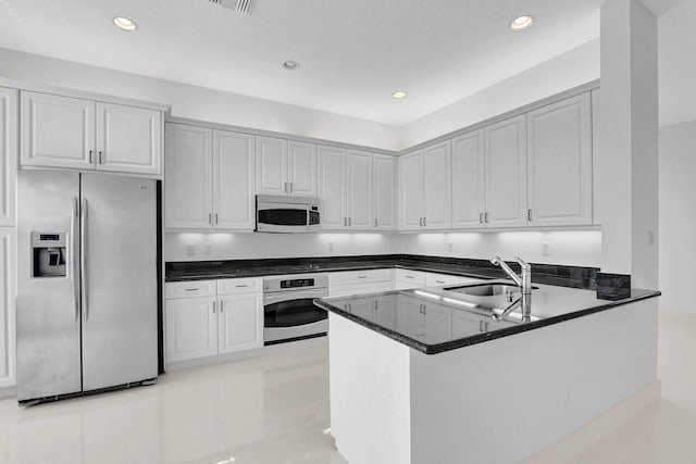 kitchen with stainless steel appliances, white cabinets, and dark stone counters