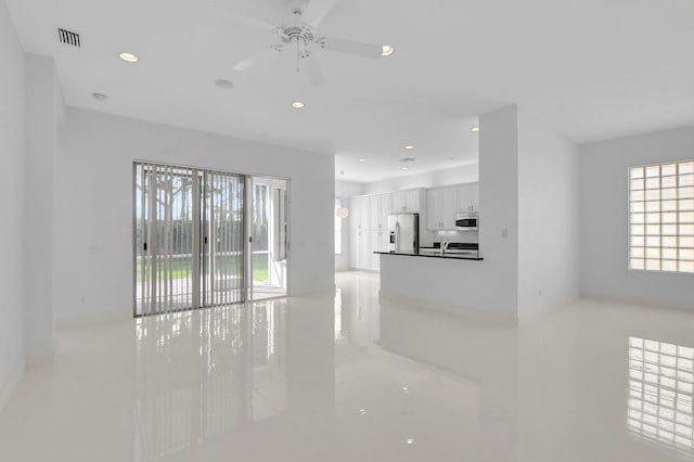 unfurnished living room featuring ceiling fan and sink