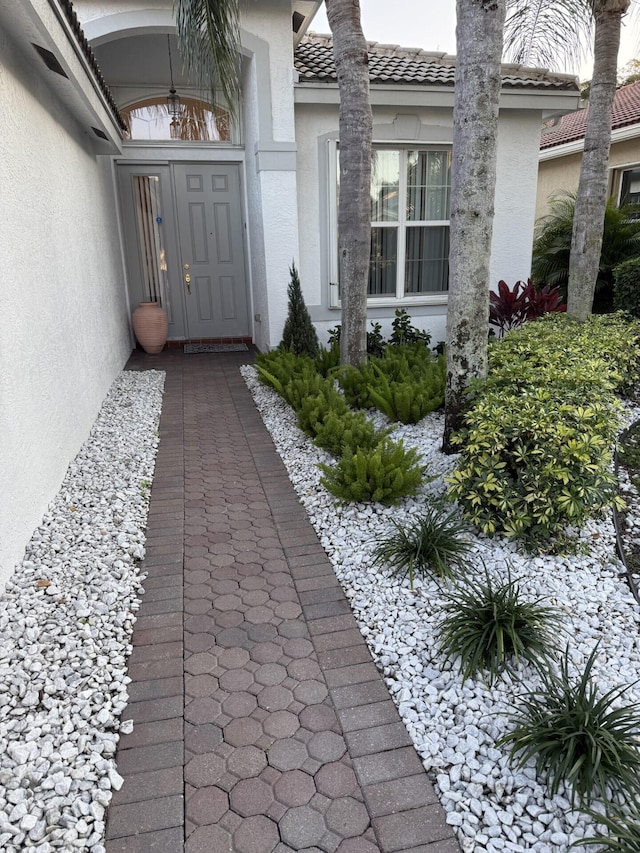 entrance to property with a tile roof and stucco siding