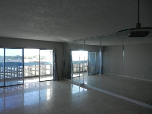 empty room with a textured ceiling and a water view