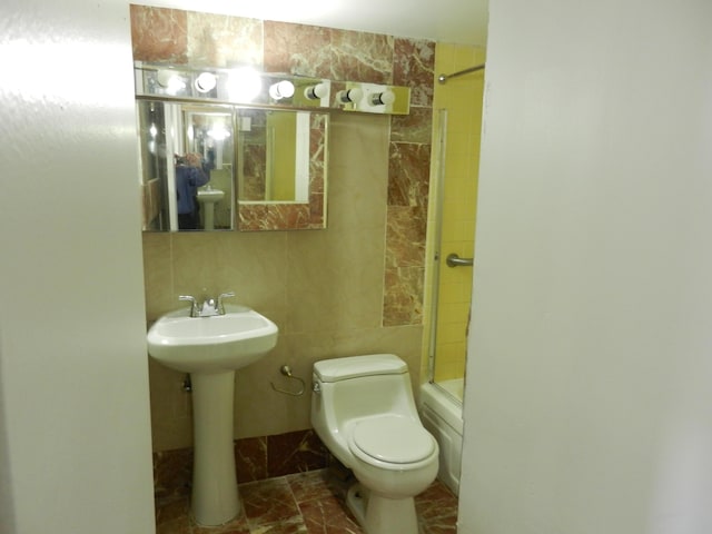 full bathroom featuring tile walls, sink, shower / bath combination with glass door, and toilet