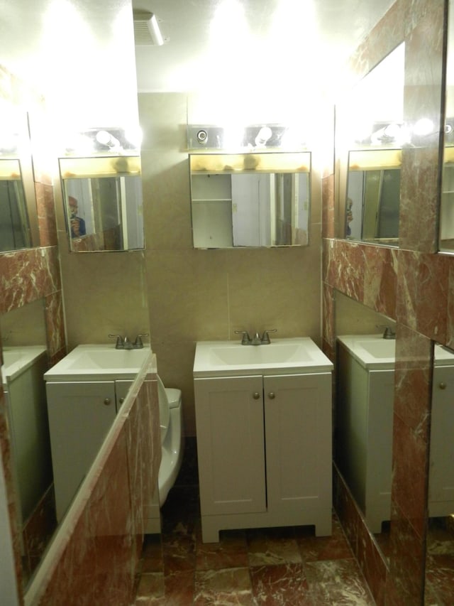 bathroom featuring tile walls, vanity, and toilet