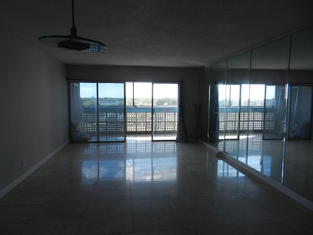 tiled empty room featuring a textured ceiling