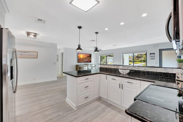 kitchen with white cabinetry, appliances with stainless steel finishes, and dark stone counters