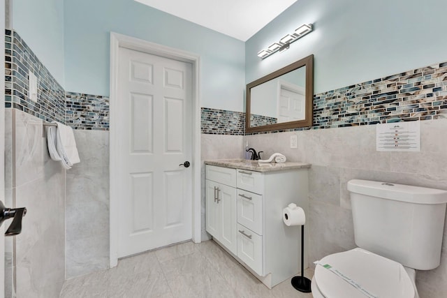 bathroom with tile walls, vanity, and toilet