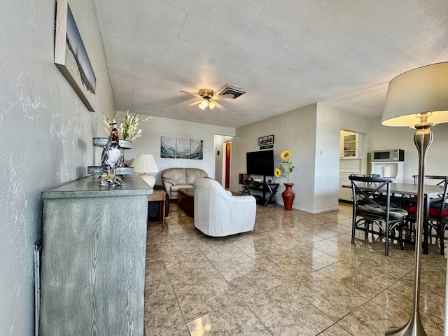 living room with a textured ceiling and ceiling fan