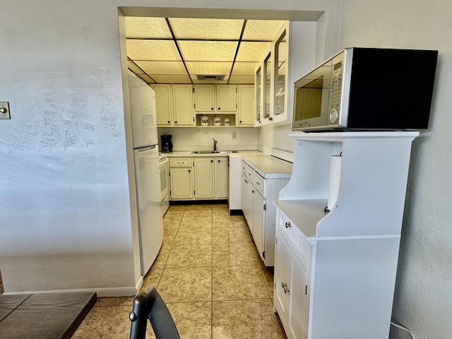 kitchen featuring sink, light tile patterned floors, a paneled ceiling, white cabinetry, and white refrigerator