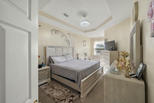 carpeted bedroom with a raised ceiling and a textured ceiling