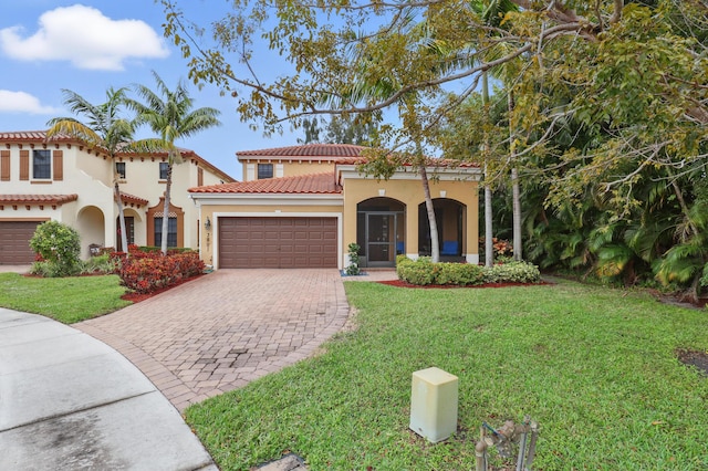 mediterranean / spanish house featuring a garage and a front lawn