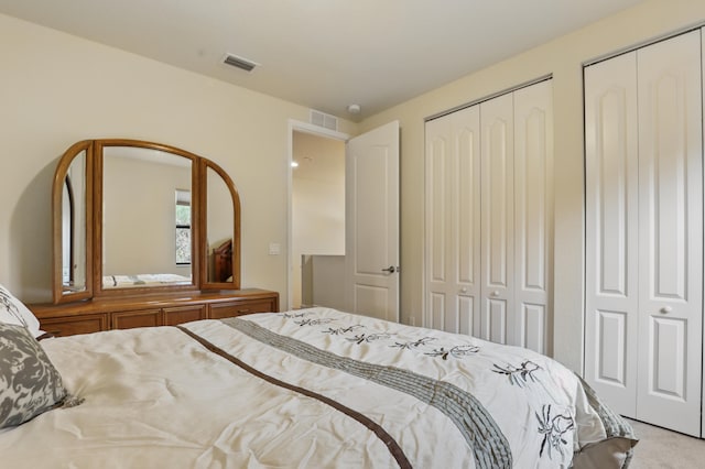 bedroom featuring light carpet and two closets