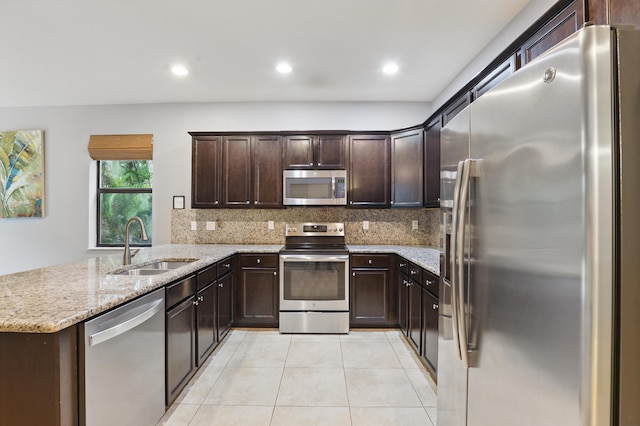 kitchen with stainless steel appliances, sink, dark brown cabinetry, and kitchen peninsula