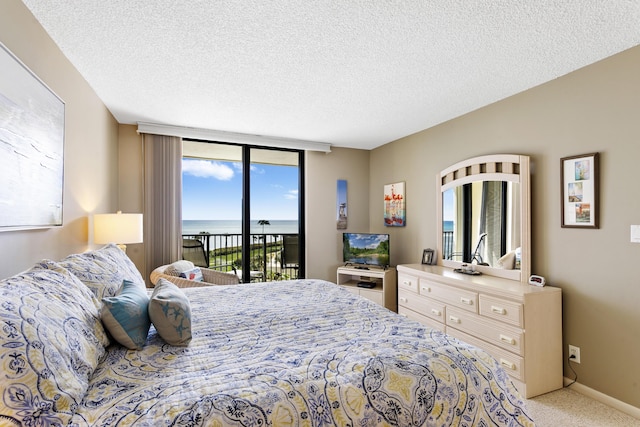 carpeted bedroom with access to exterior, expansive windows, and a textured ceiling