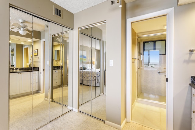 bathroom featuring vanity, ceiling fan, a shower, and a textured ceiling