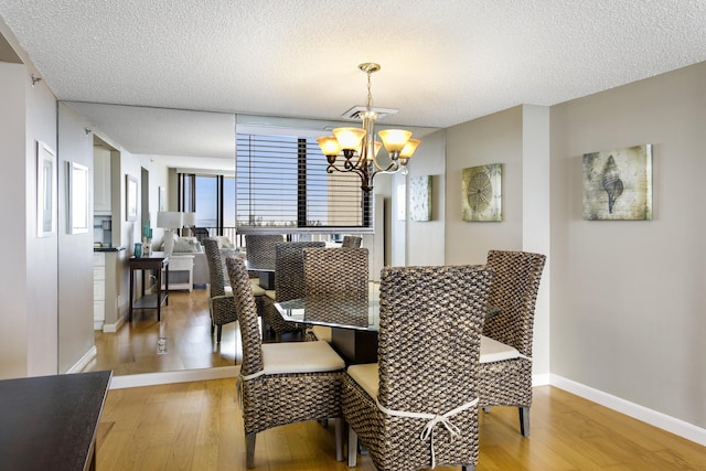 dining area with hardwood / wood-style floors, a textured ceiling, and a notable chandelier