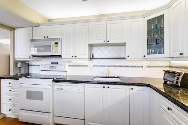 kitchen with sink, wood-type flooring, white appliances, dark stone counters, and white cabinets