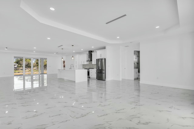 unfurnished living room featuring a raised ceiling and sink