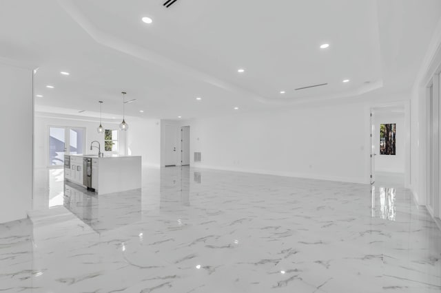 unfurnished living room with a raised ceiling and sink